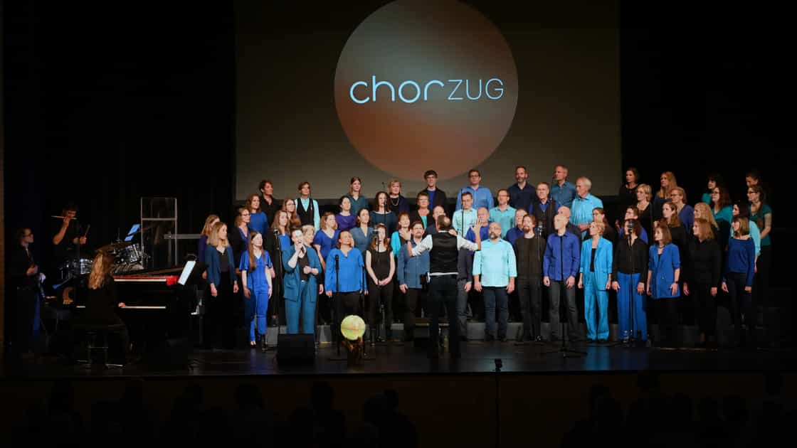 Der chor zug auf der Bühne beim Jahreskonzert "element of nature" am 18. November 2023. Im Hintergrund das Chor-Logo.