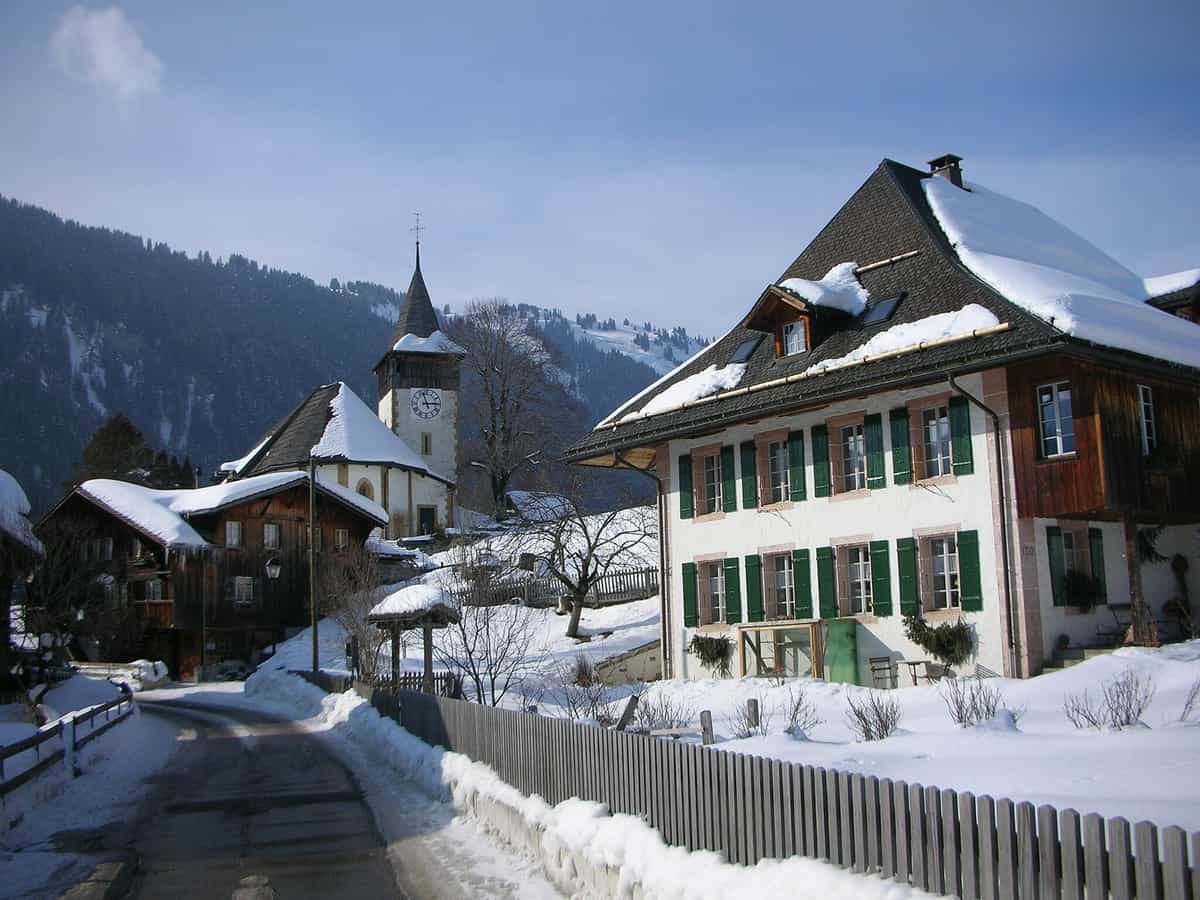 Kirche (links im Bild) und Kirchgemeindehaus (rechts im Bild) in Zentrum des Dorfes Lauenen (Schweiz) im Winter