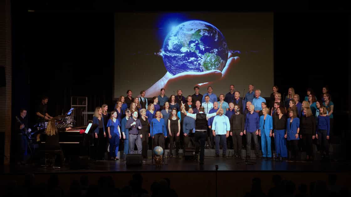 Der chor zug auf der Bühne beim Jahreskonzert "element of nature" am 18. November 2023. Im Hintergrund eine Weltkugel.