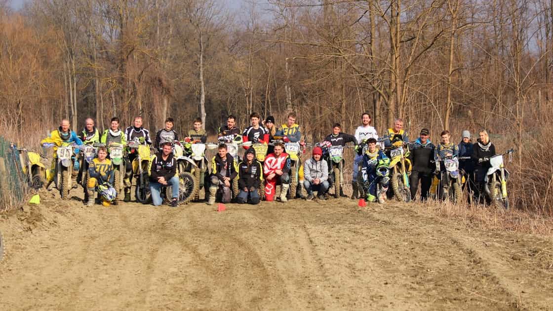 Image représentant 25 membres du club lors d'un entrainement de motocross sur une piste en Italie. Les pilotes se trouveent sur une partie du circuit de motocross, certains sont debout et d'autres sont assis sur leur moto.