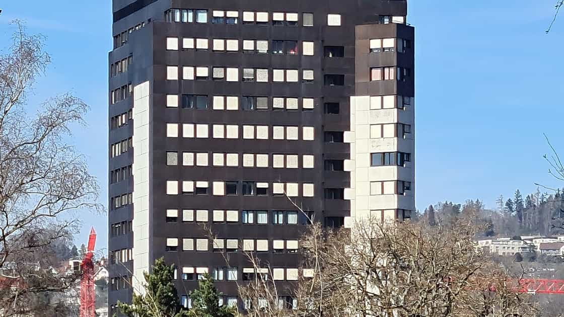 Betonhochhaus mit Spital-H an der dunkelbraunen Fassade