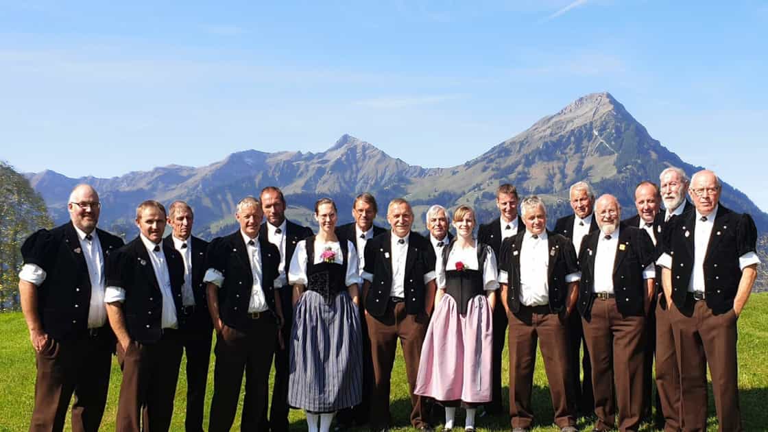 The yodelling club Blüemlisalp Scharnachtal poses in its traditional costumes, with the Niesen chain in the background