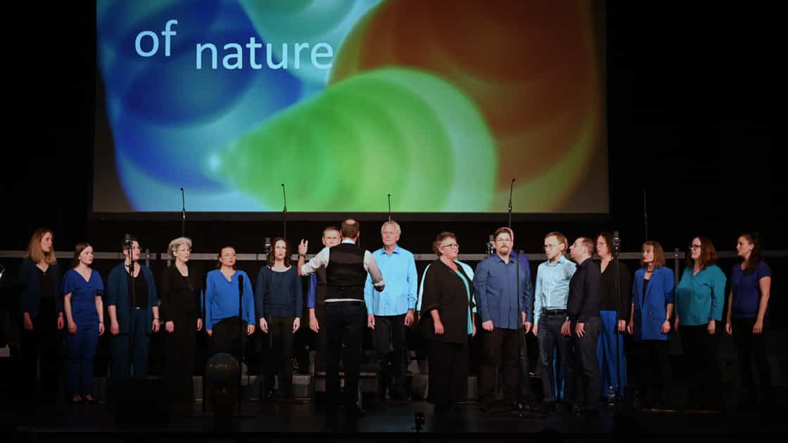 Der kleine chor zug auf der Bühne beim Jahreskonzert "element of nature" am 18. November 2023. Im Hintergrund das Konzertplakat.